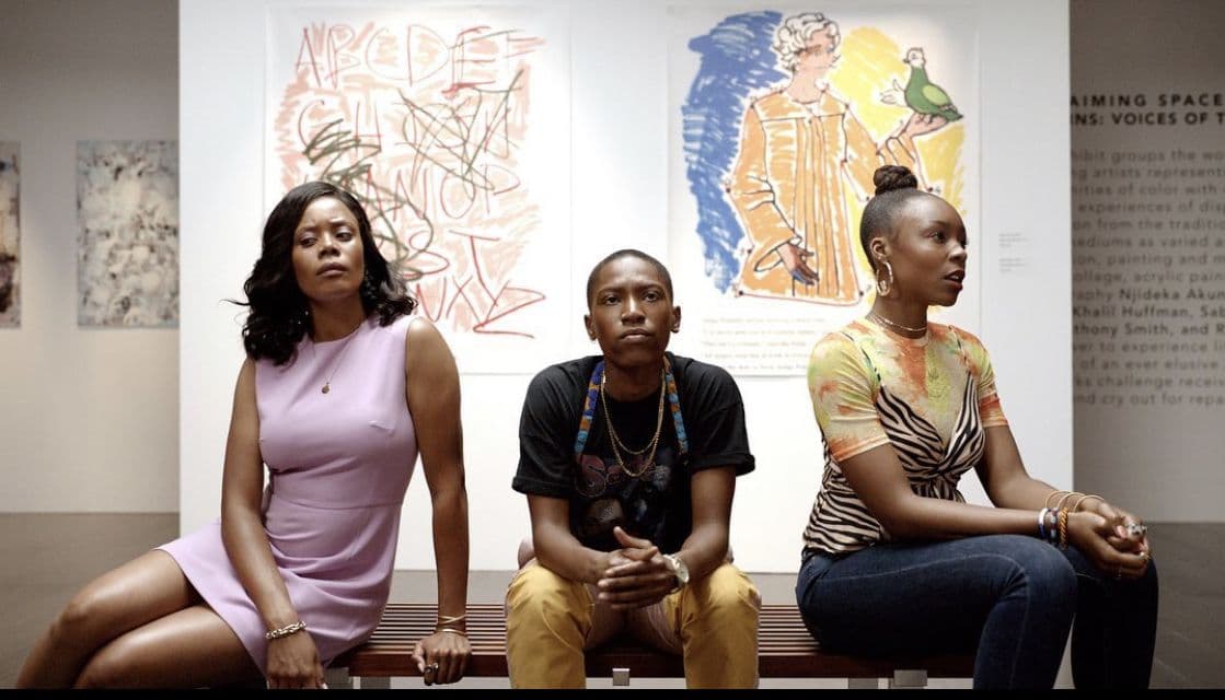 Still from the series "Twenties" shows three young people sitting on a bench in a museum. A series of artworks can be seen on the walls behind them.