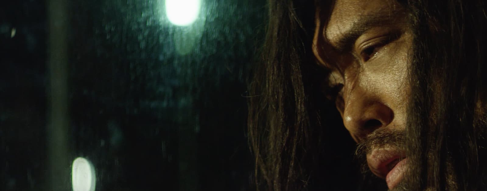 Waikiki (2020). Film still courtesy of filmmaker Christopher Kahunahana. A Native Hawaiian person looks out from a car window in pain.