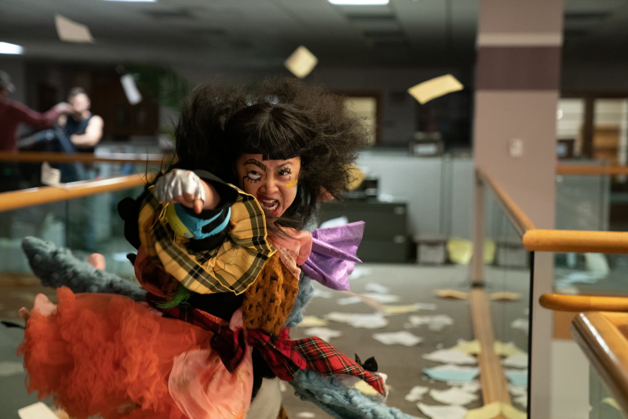 Still from Everything Everywhere All at Once directed by Daniel Kwan and Daniel Scheinert. An asian woman in a fighting stance wearing a lot of different articles of clothing. In the background is an office with papers scattered all over.