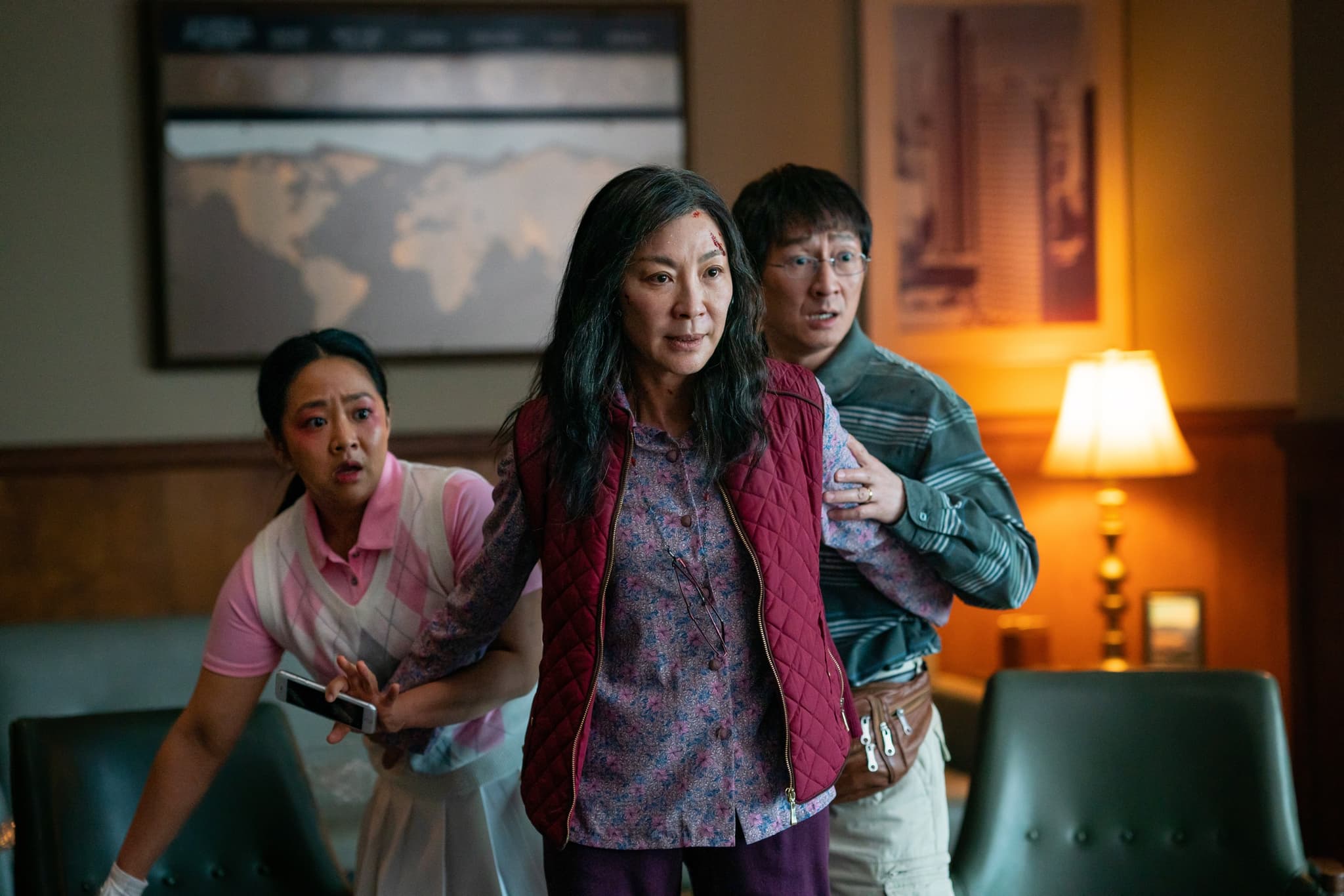 A still from Everything Everywhere All at Once. An asian woman standing in a defensive stance, protecting the two people behind her,