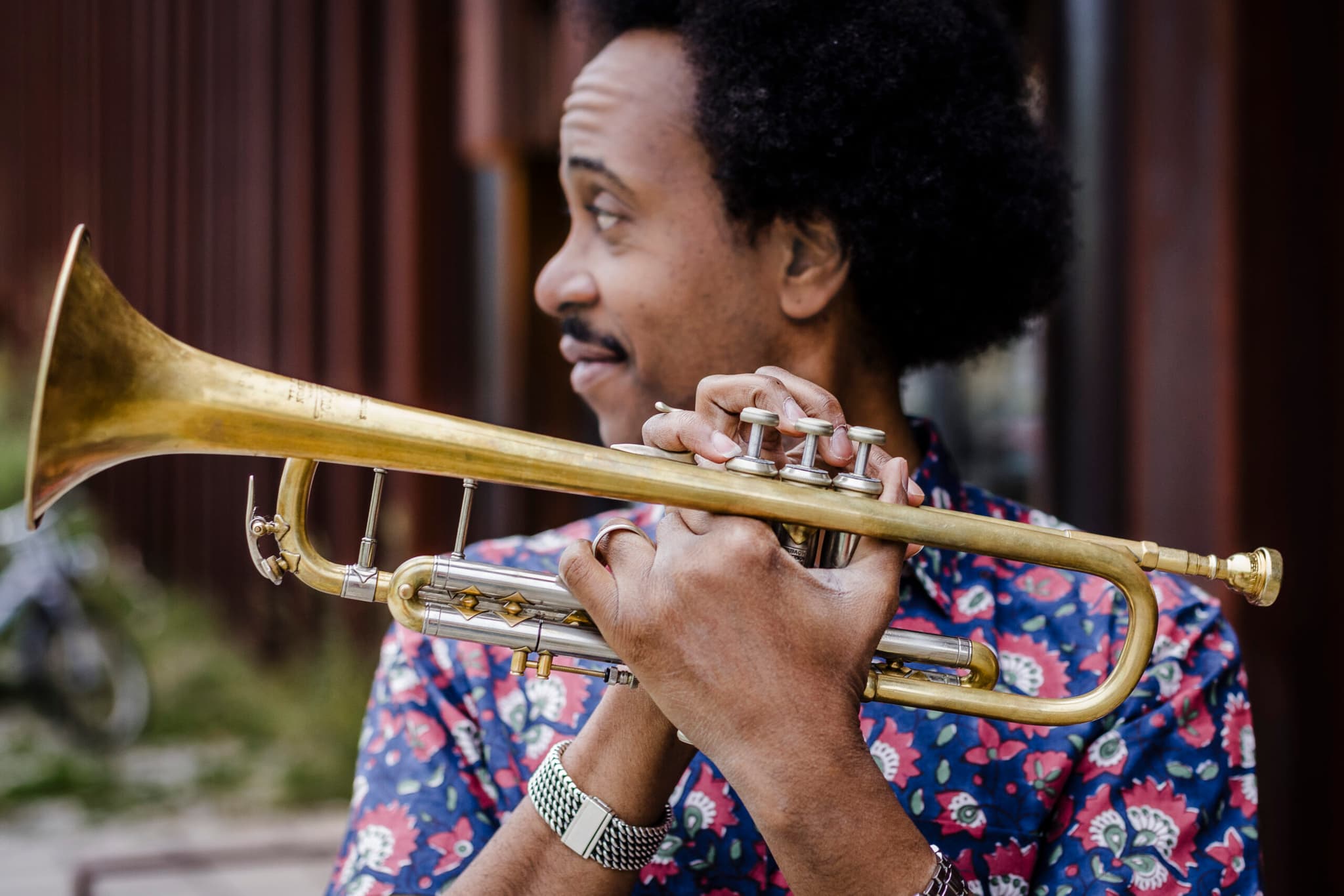 A headshot of Jonathan Finlayson. He is a Black man, he has a mustache and afro. He is holding a trumpet.