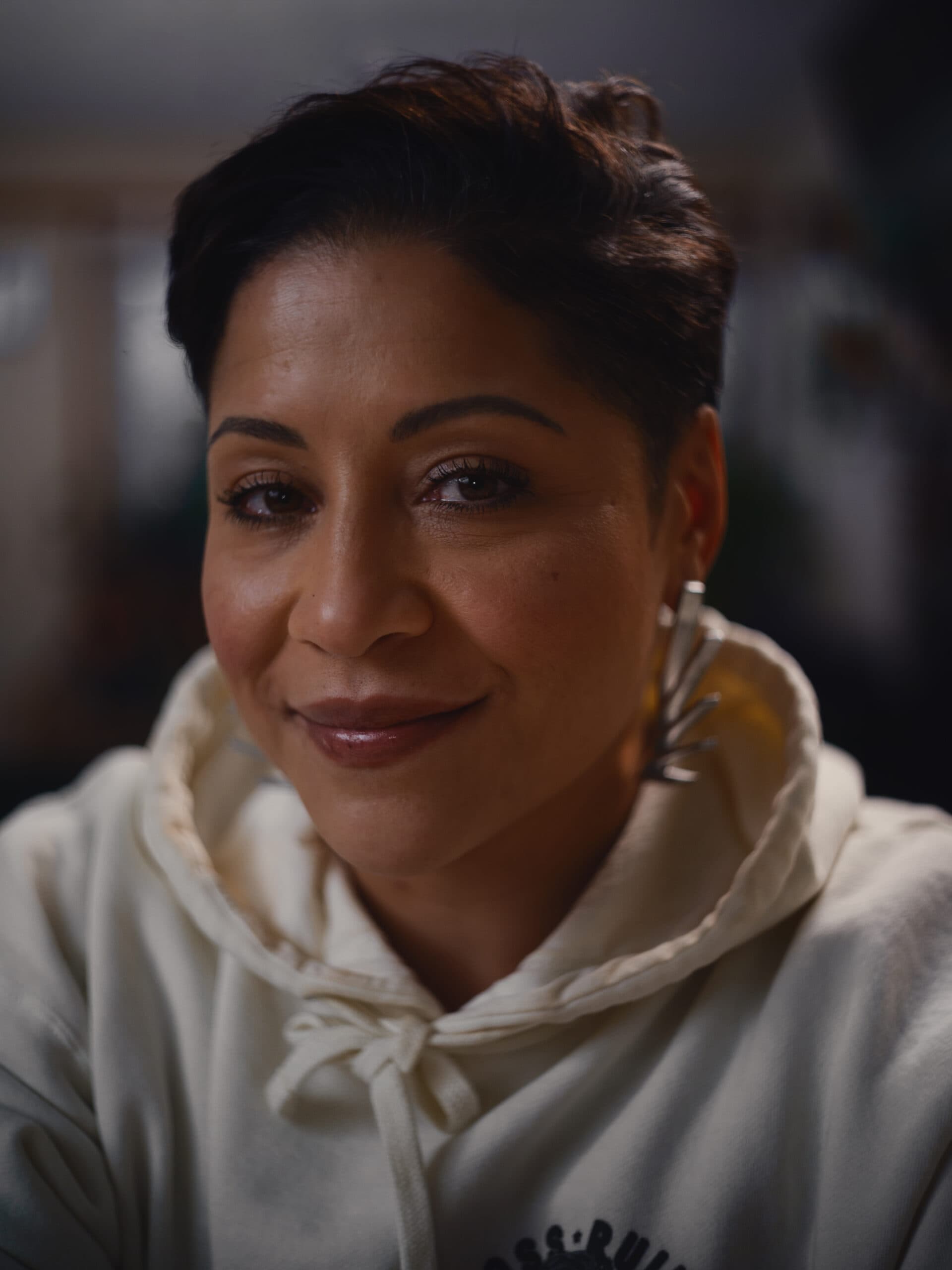A headshot of Jeanette Lloyd. She has a soft smile and short brown hair. She is wearing a white hoodie.