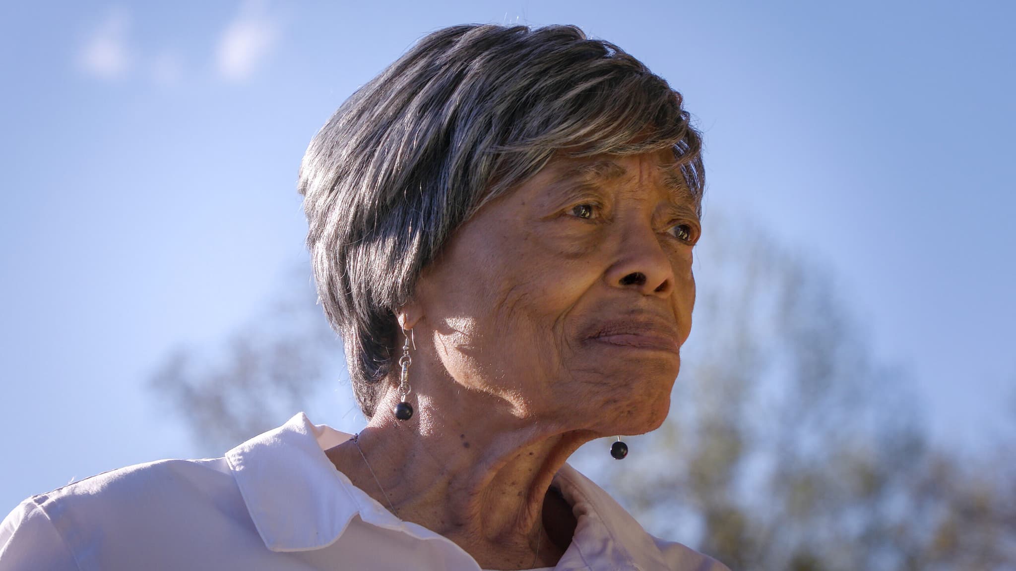 A photo of an older Black woman with silver hair looking out into the distance.