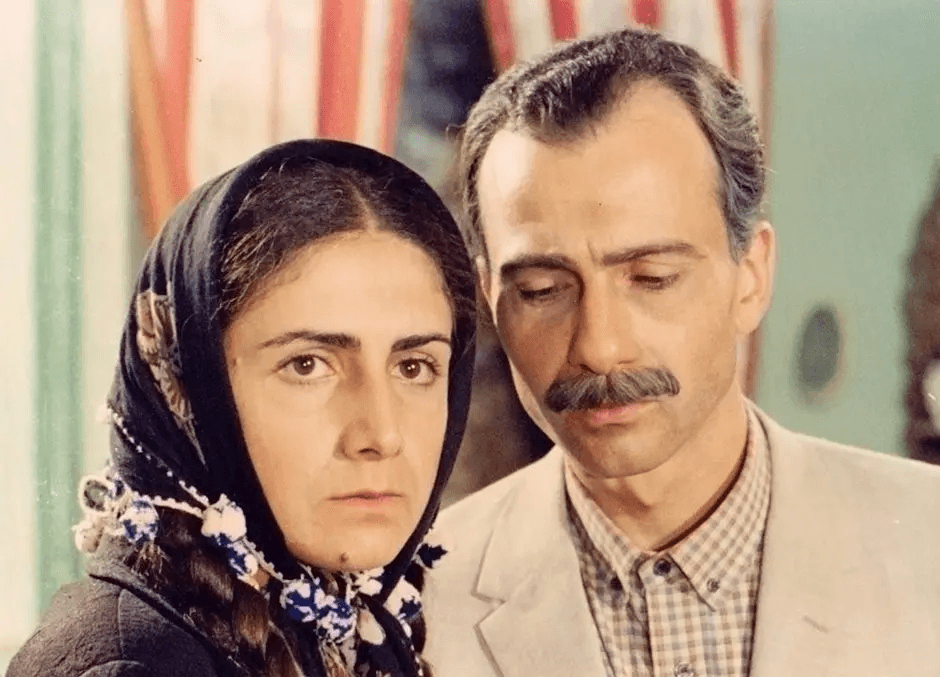 A still from Return to Haifa shows a Palestinian couple standing with one another. The woman has a stricken expression and the man is looking down, he seems to be in contemplation or sorrow.