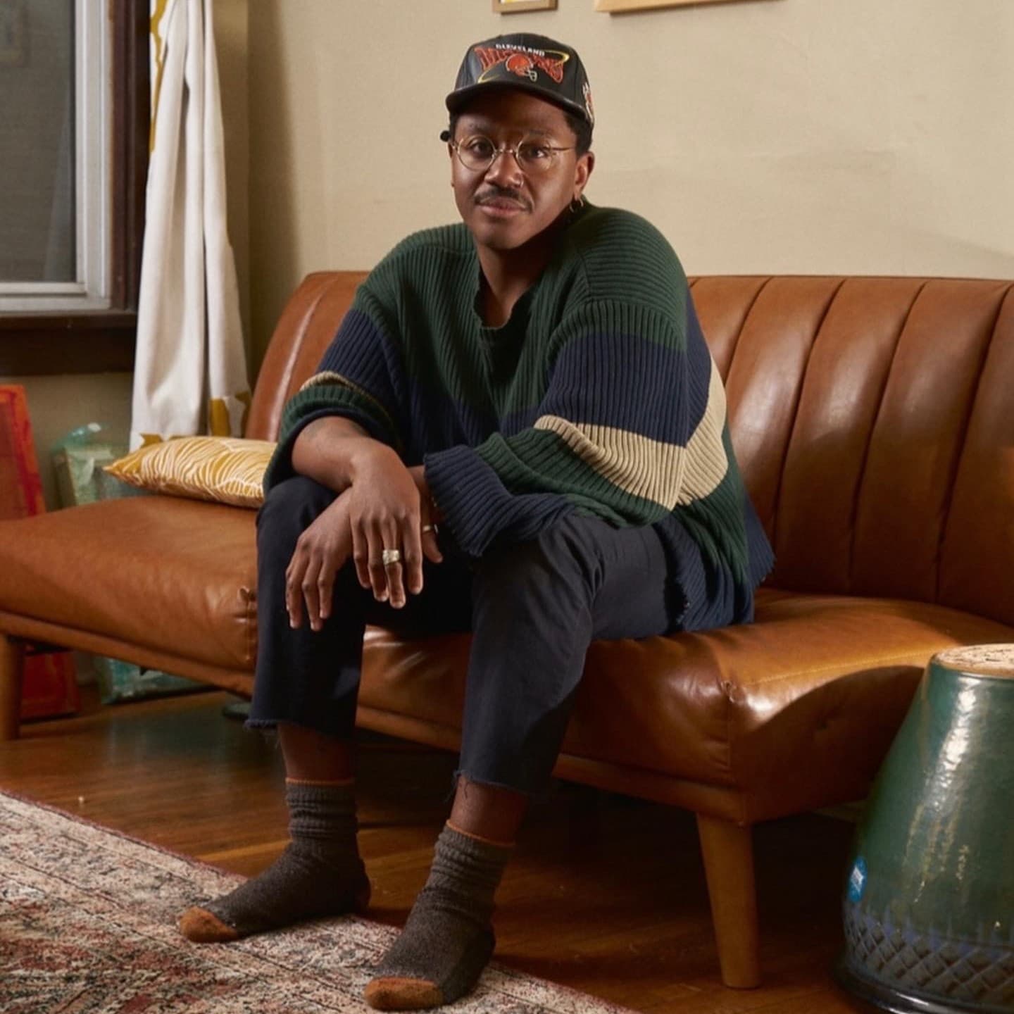 A photograph shows a portrait of Cameron A. Granger sitting on a leather couch inside a home space.