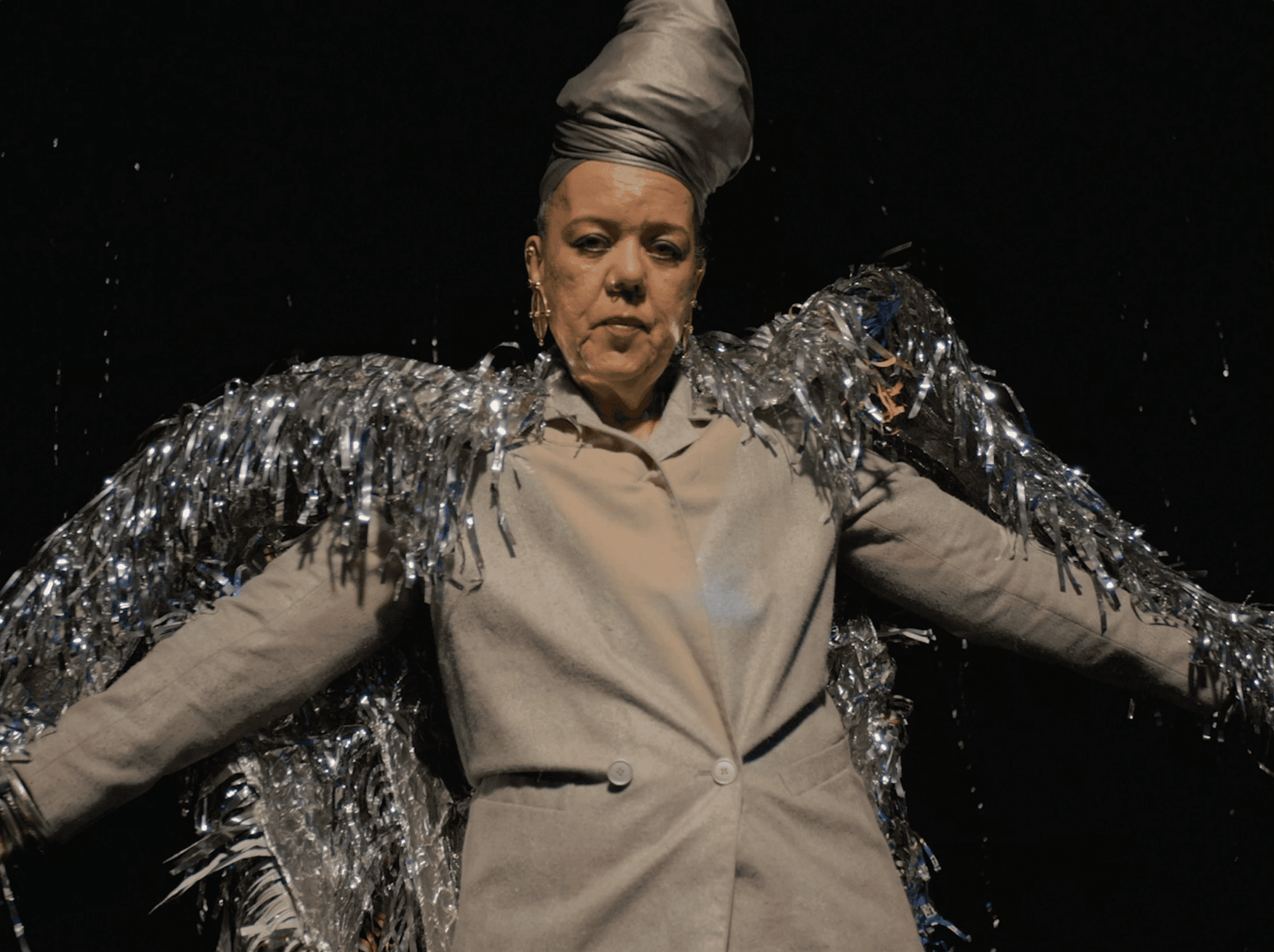 A still image from T by Keisha Rae Witherspoon shows a Black person with their arms spread wide as if flying, wearing a homemade costume of wings.