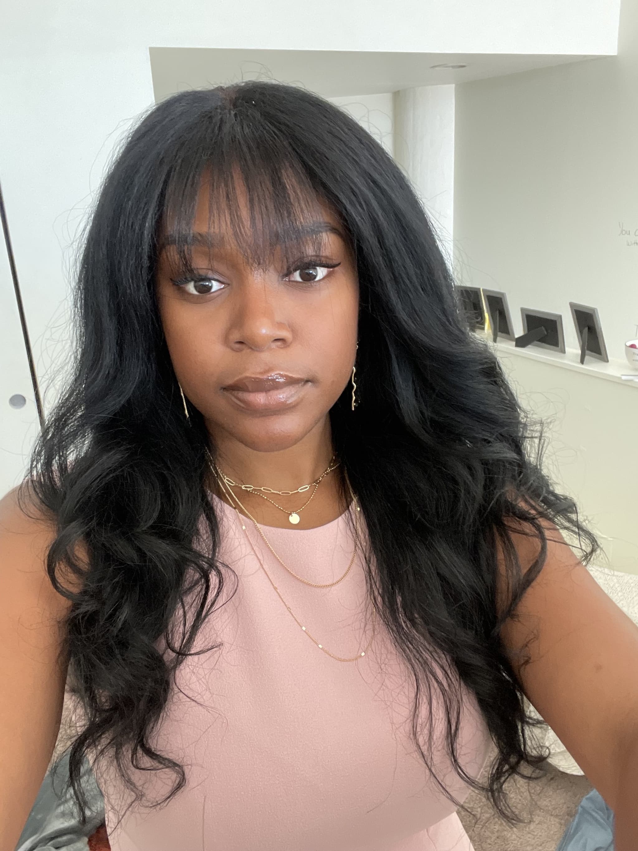 A selfie of Yasmine Carruthers wearing a casual pink top, and gold jewelry. She has long black hair with curls that reach past her shoulders.