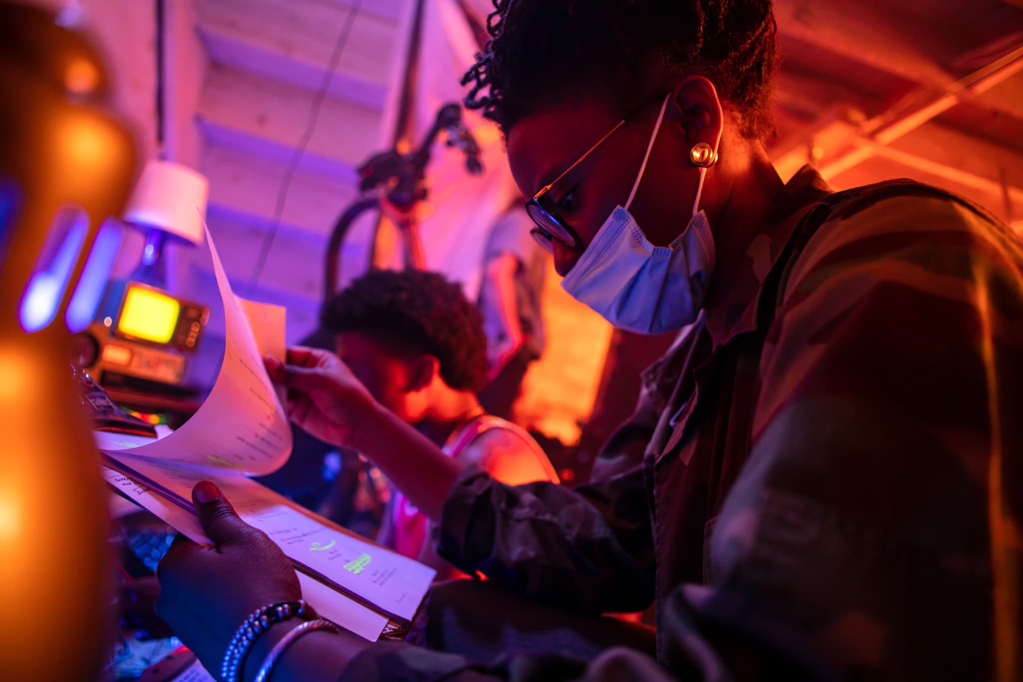 Director Jasmine Lynea reviews some documents on set of a film production, the lighting is purple and red.