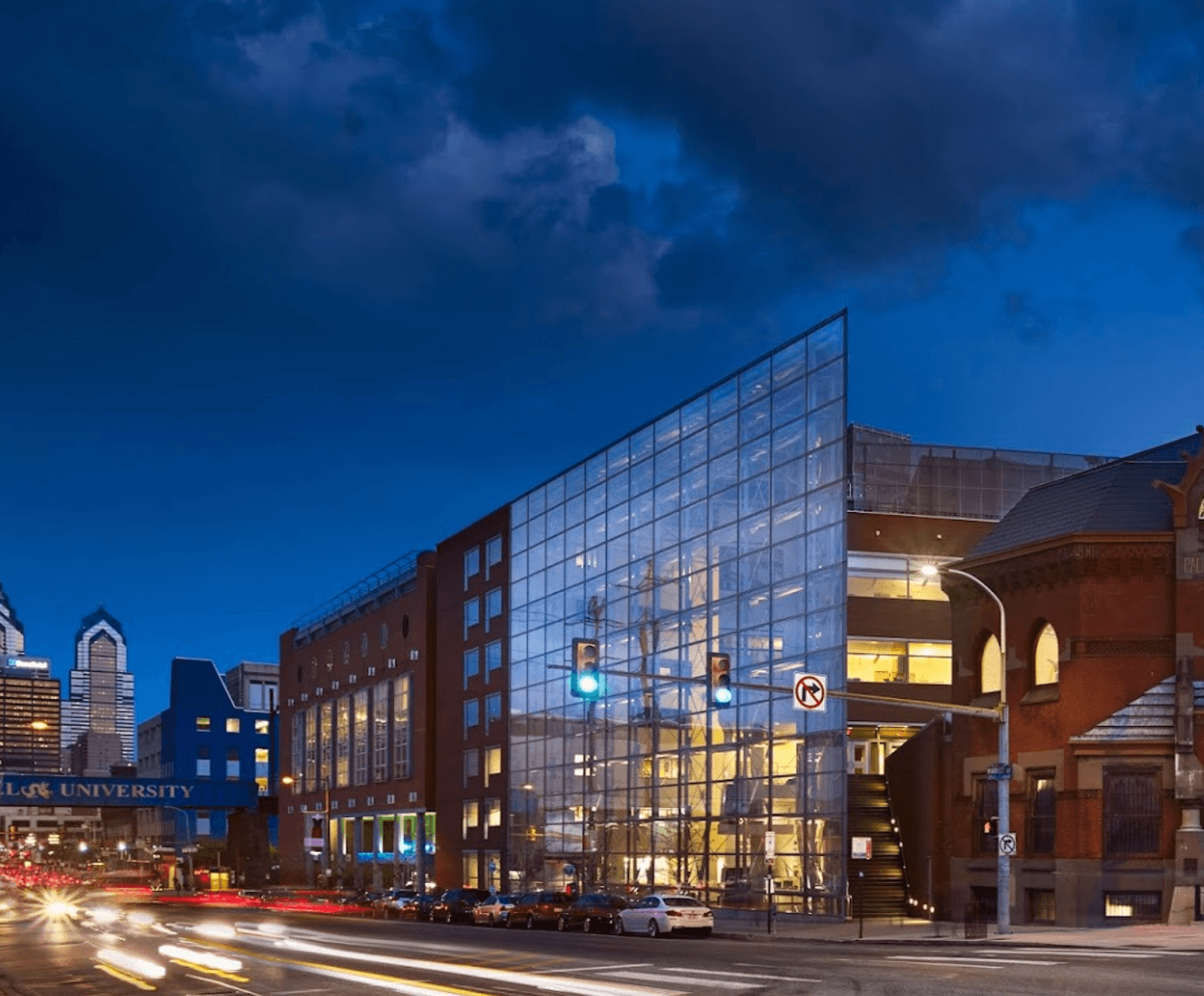 A photo of the Bossone Center at night, which features a glass panel front entrance on a busy street.