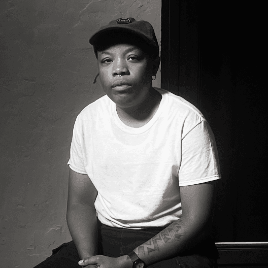 A photograph shows a black and white portrait of LaTajh Weaver sitting.