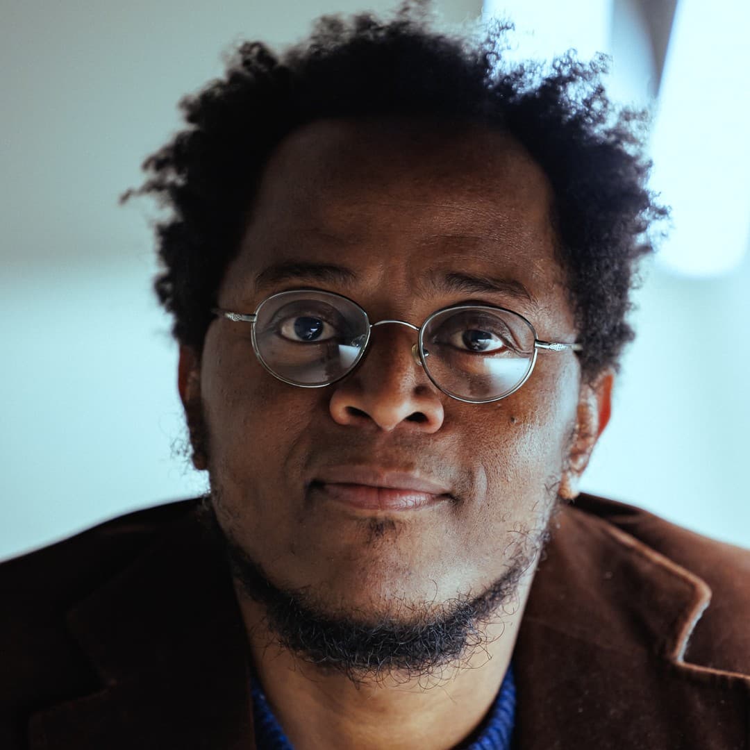 A photograph shows a portrait of Alain Kassanda.