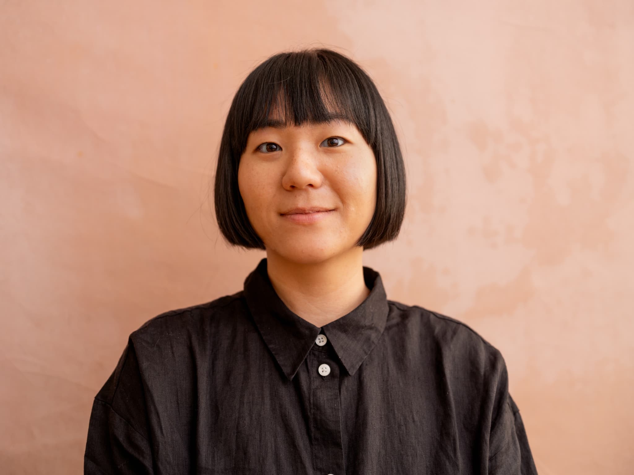 A headshot of Catherine Lee. She is an Asian woman, she has a short black bob. She is smiling softly at the camera.