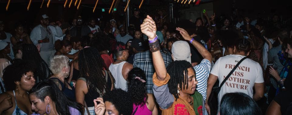 A crowd shot of people dancing at a party. The lights glow around them.