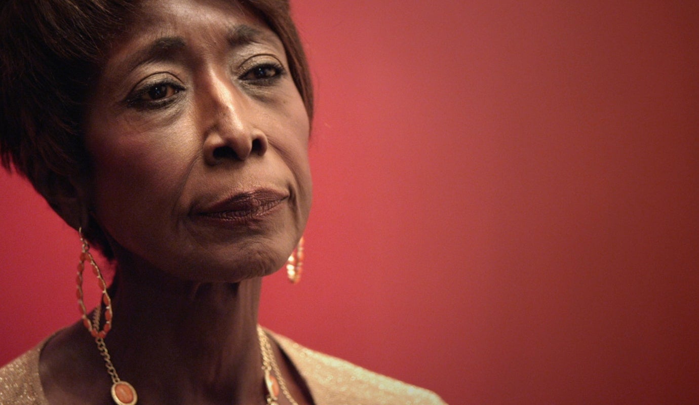 A still from Happy Birthday to a Beautiful Women shows a close-up of an older Black woman. She has a contemplative look on her face.