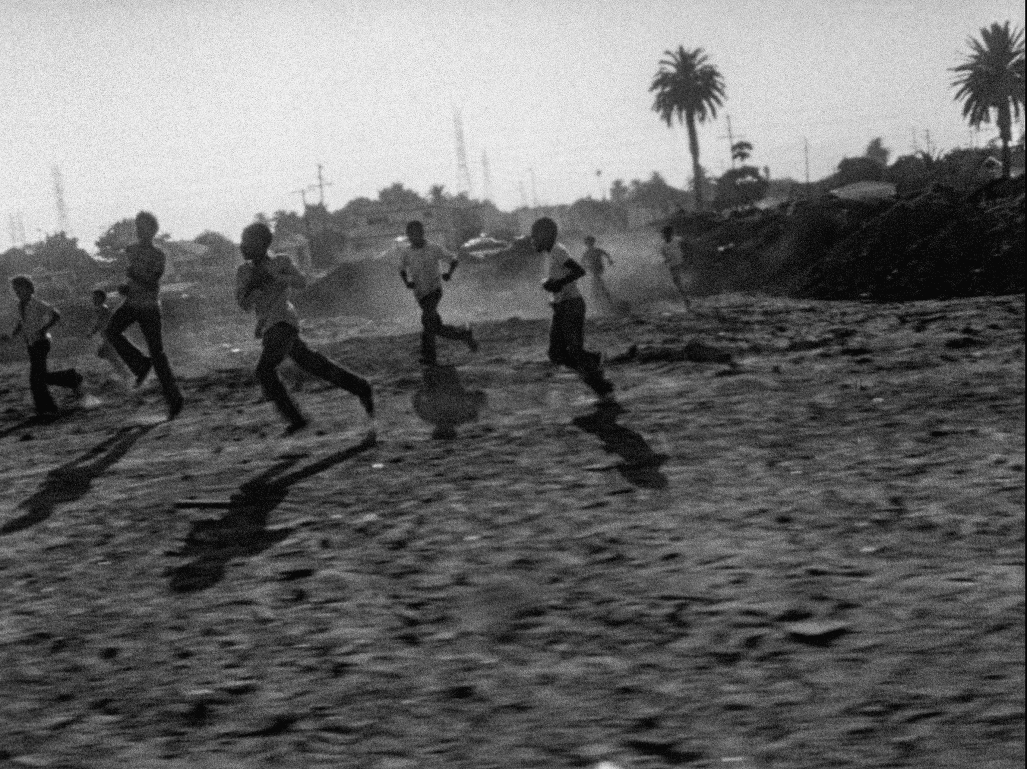 A black and white image from the film Killer of the Sheep (1978). It features a group of Black kids running on a field.