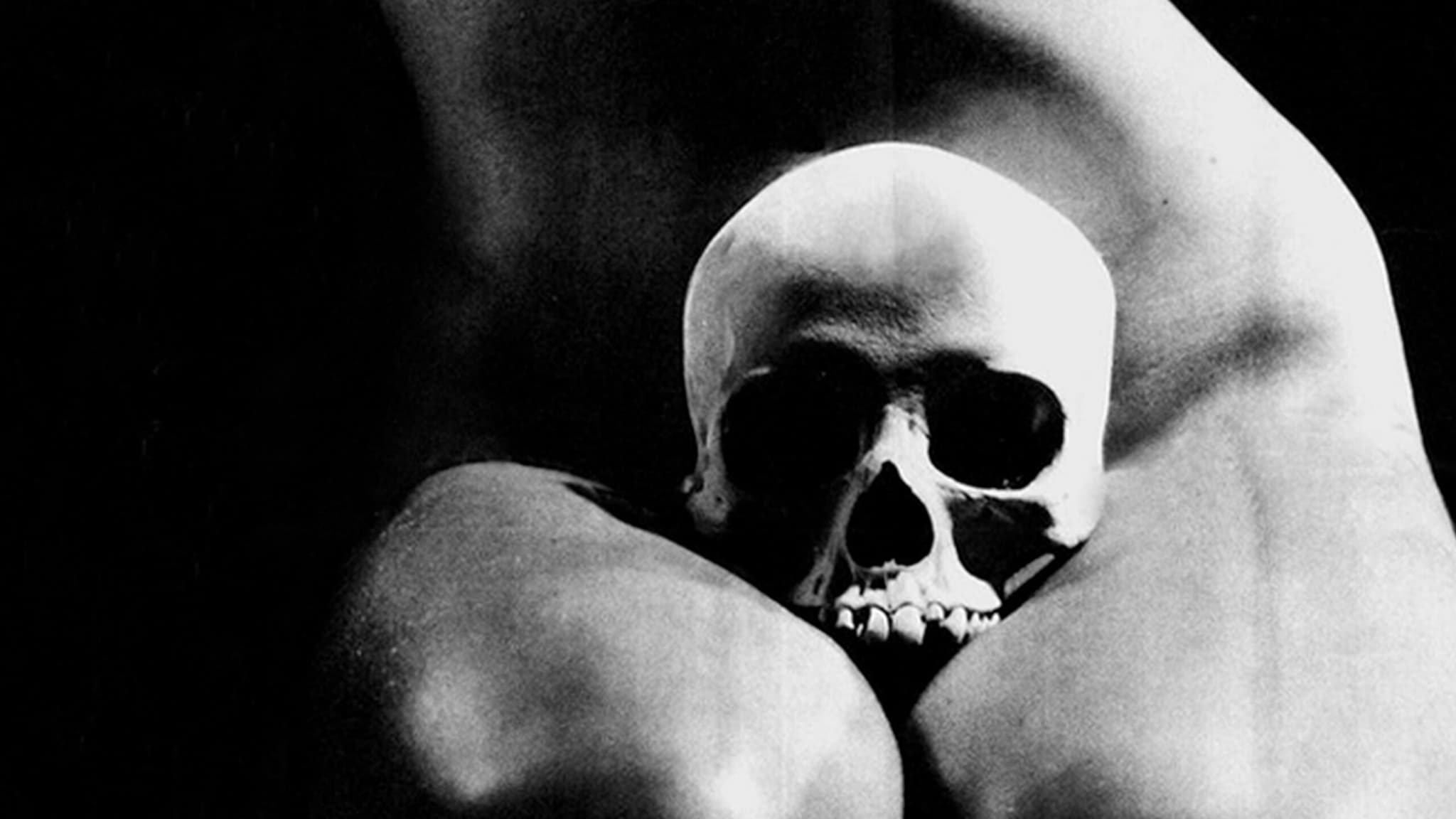 A black and white image of a skull on someone's lap covering the lower abdomen.