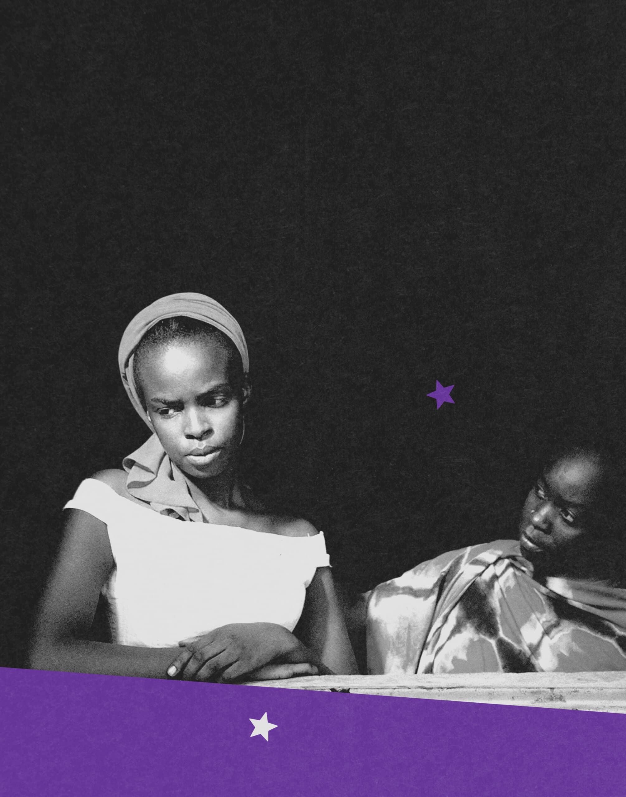 Black-and-white image of two women standing side by side. The woman on the left wears a headscarf, looking down with a serious expression, while the woman on the right looks toward her.