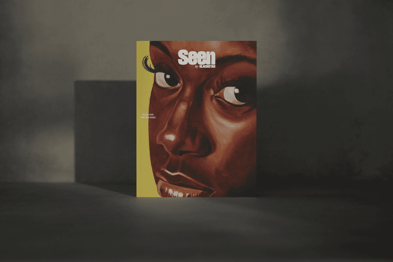 A mock-up of the Seen 010 cover on a black and tan background. The cover image is a reimagined painting of the Girl with a Pearl Earring featuring a Black girl looking directly at the camera with a strong gaze. She has long, detailed eyelashes, and her expression is calm but intense. Overlaid on top is the “Seen” logo.