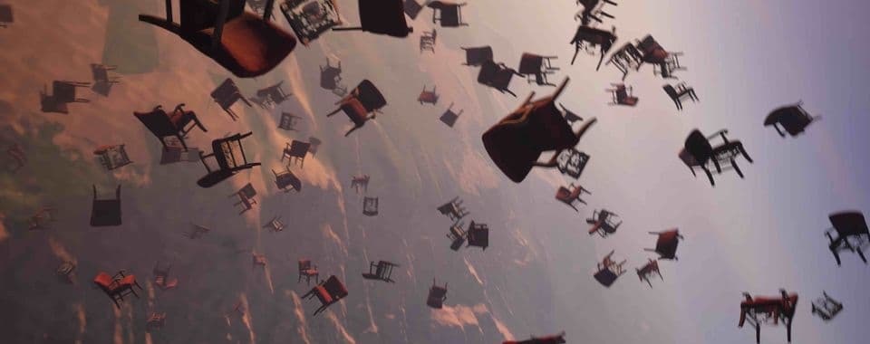 A film still from An Impossible Address shows dozens of chairs falling from the sky toward a desert landscape.
