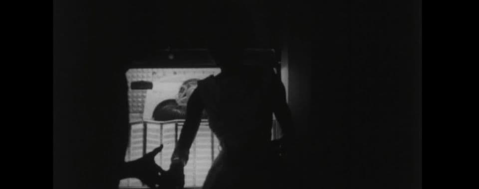 A black-and-white film still from I Wonder Shall I Fly shows a glowing jukebox illuminating a woman in a dress and the hand of her dance partner.