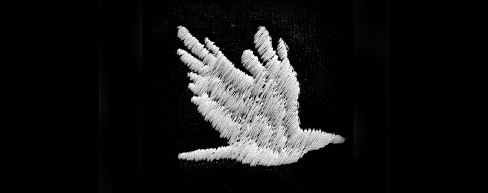 A film still from Our Bodies Ours shows an embroidered white bird mid-flight on a black background.