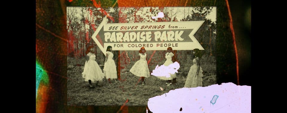 A film still from Same Water shows a black-and-white photo of five young Black women standing outdoors in poofy, patterned dresses beneath a large sign that reads, “See Silver Springs from…Paradise Park for Colored People.” The image is overlaid with a scan of a plant leaf painted in orange, green, and red.