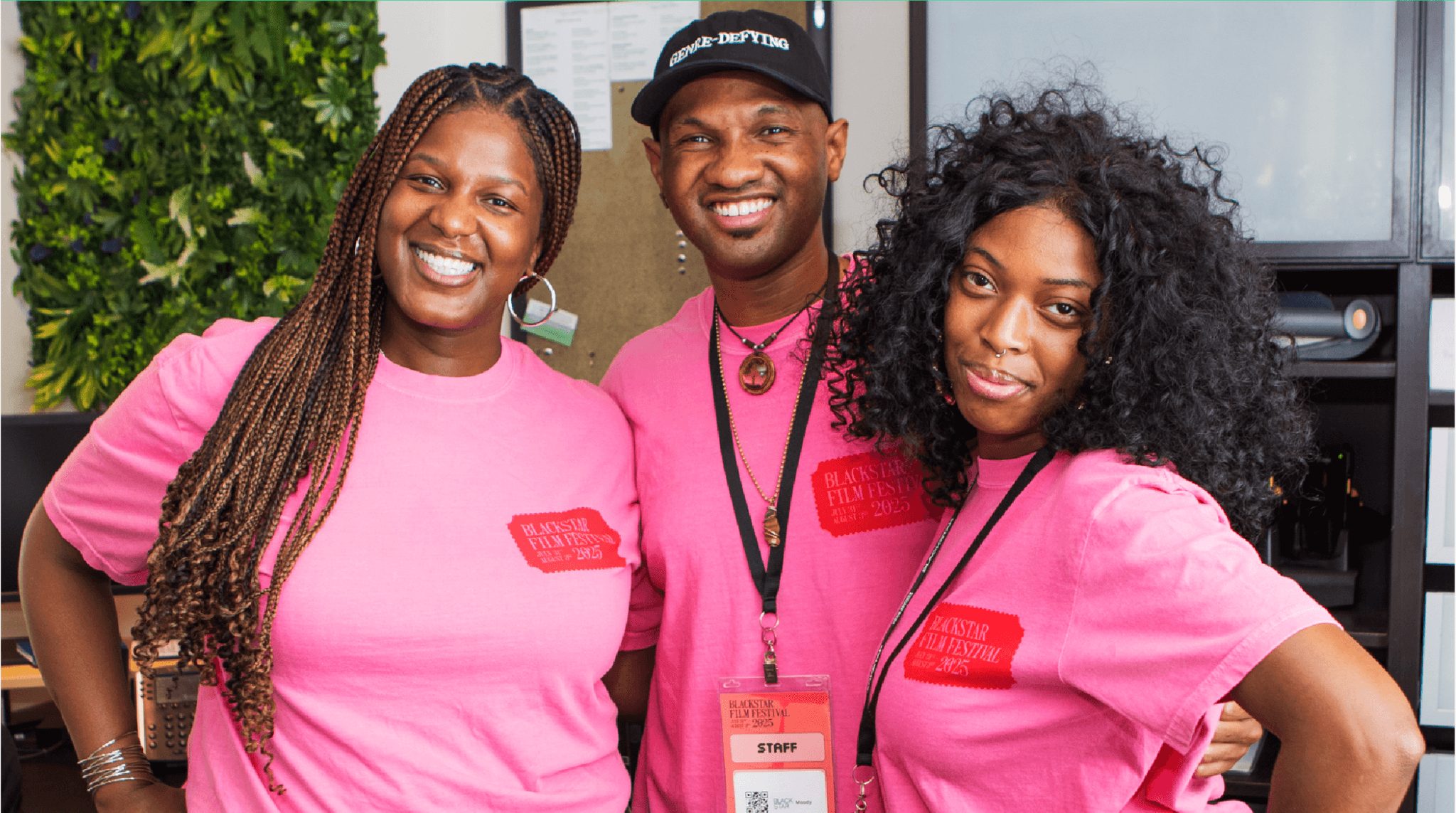 A photo of three BlackStar Film Festival employees standing arm-in-arm and smiling. They all have on pink BlackStar Film Festival t-shirts.