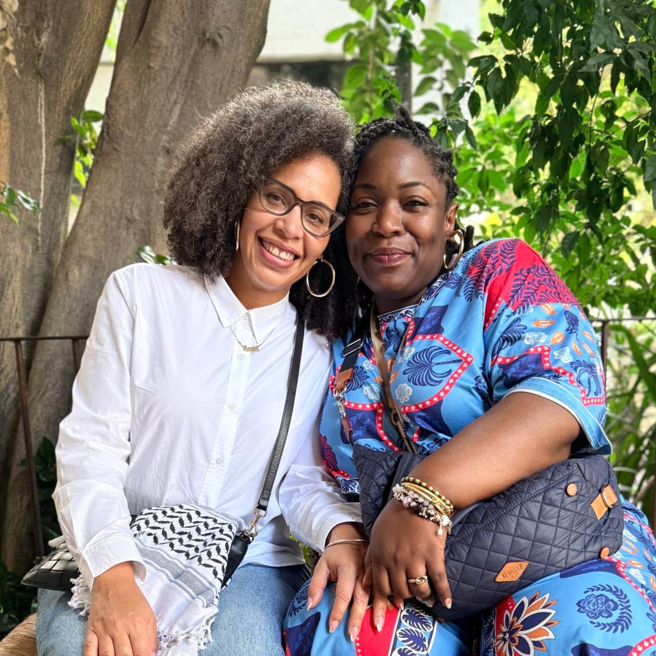 Loira Limbal and Rafiah Vitalis from Firelight Media posing together for a photo. They are arm-in-arm and are smiling.