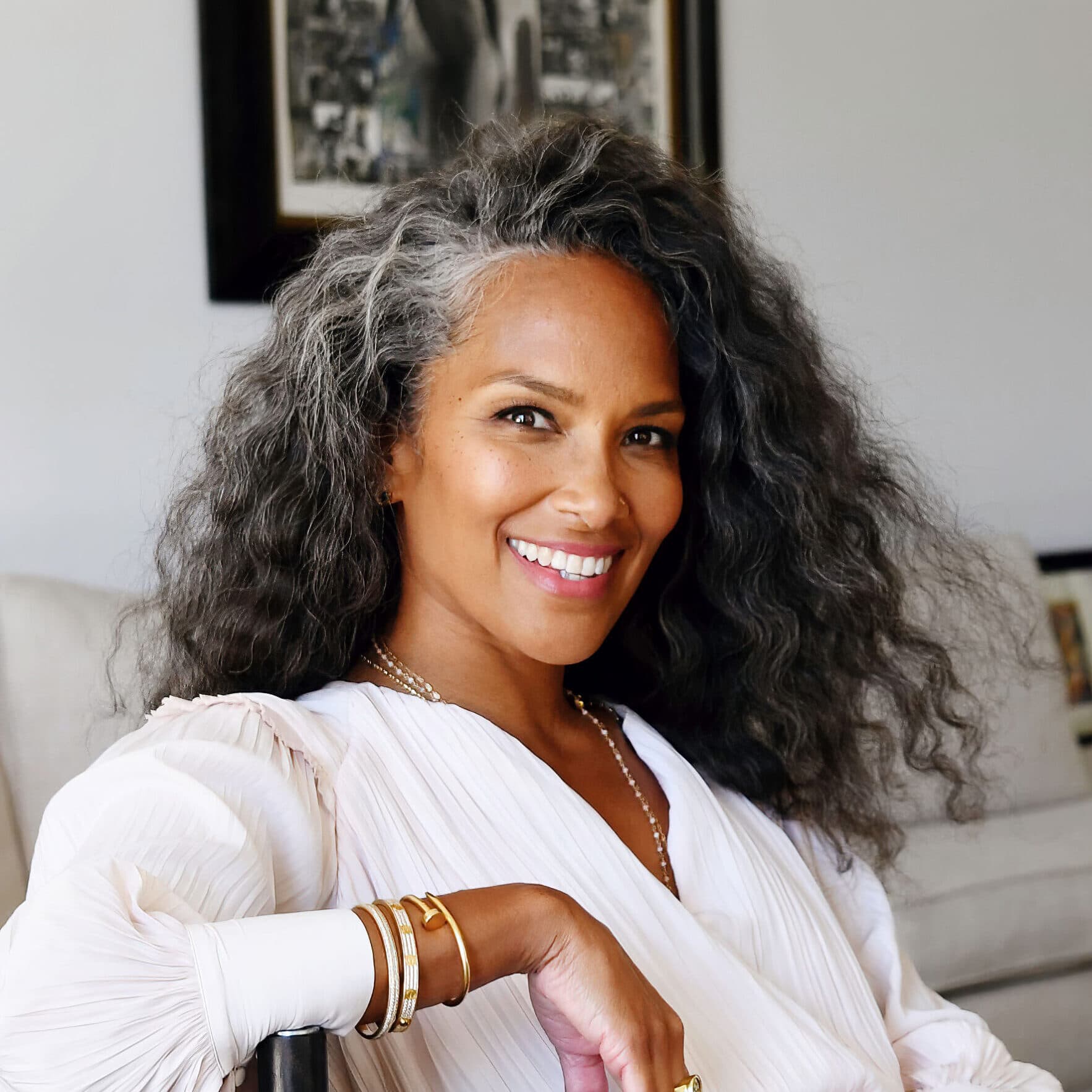 A headshot of Mara Brock Akil, she is a Black woman. She has long gray hair and is smiling at the camera.