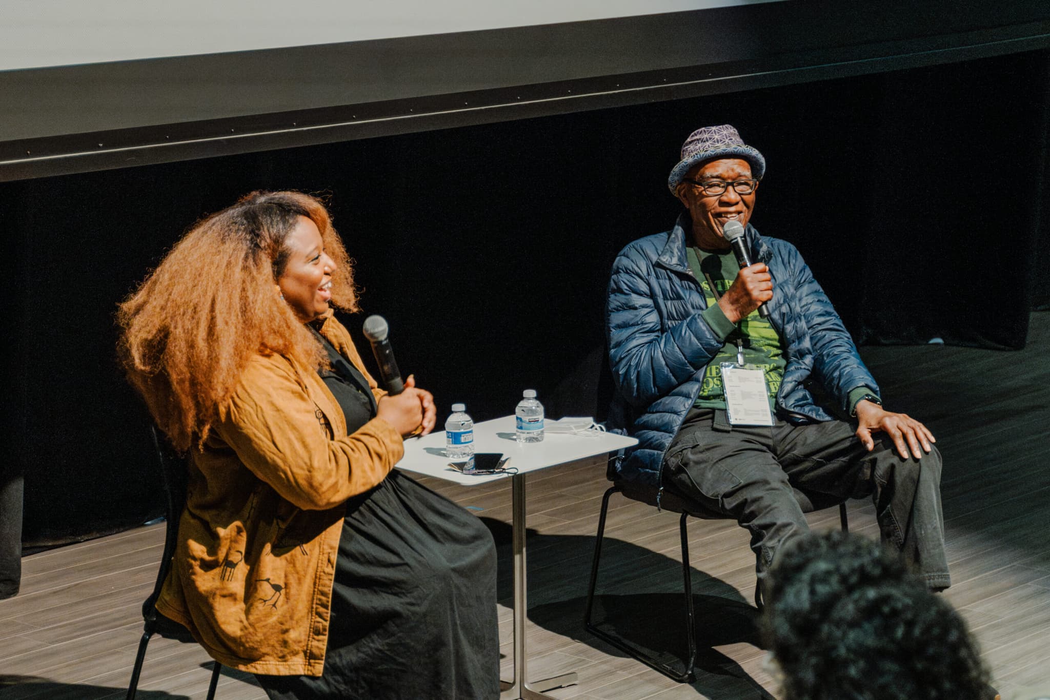 A photo of Maya S. Cade and Ben Caldwell on stage. They are mid-discussion.