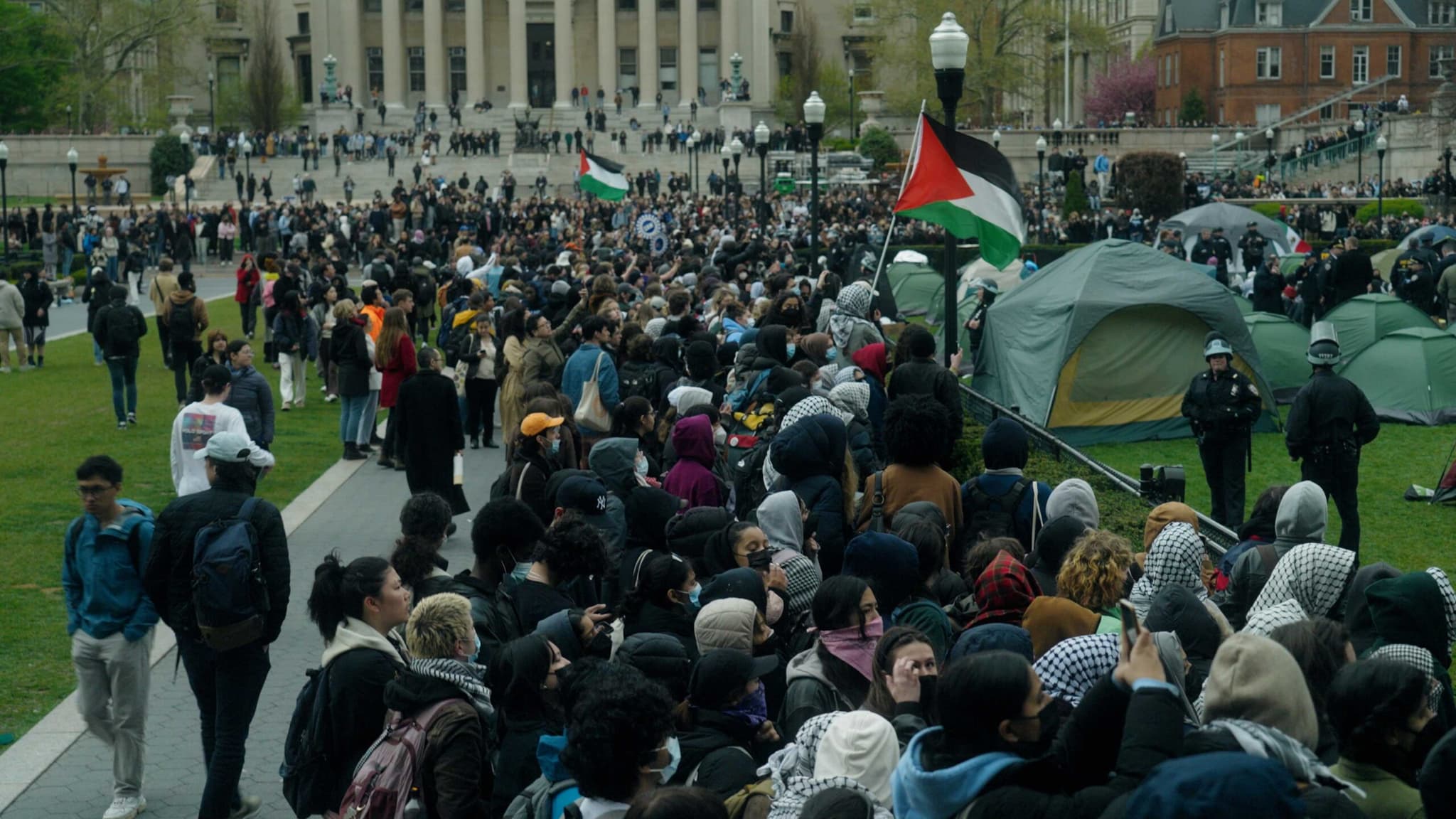Protesters gather on Columbia University campus holding the national flag of Palestine.
