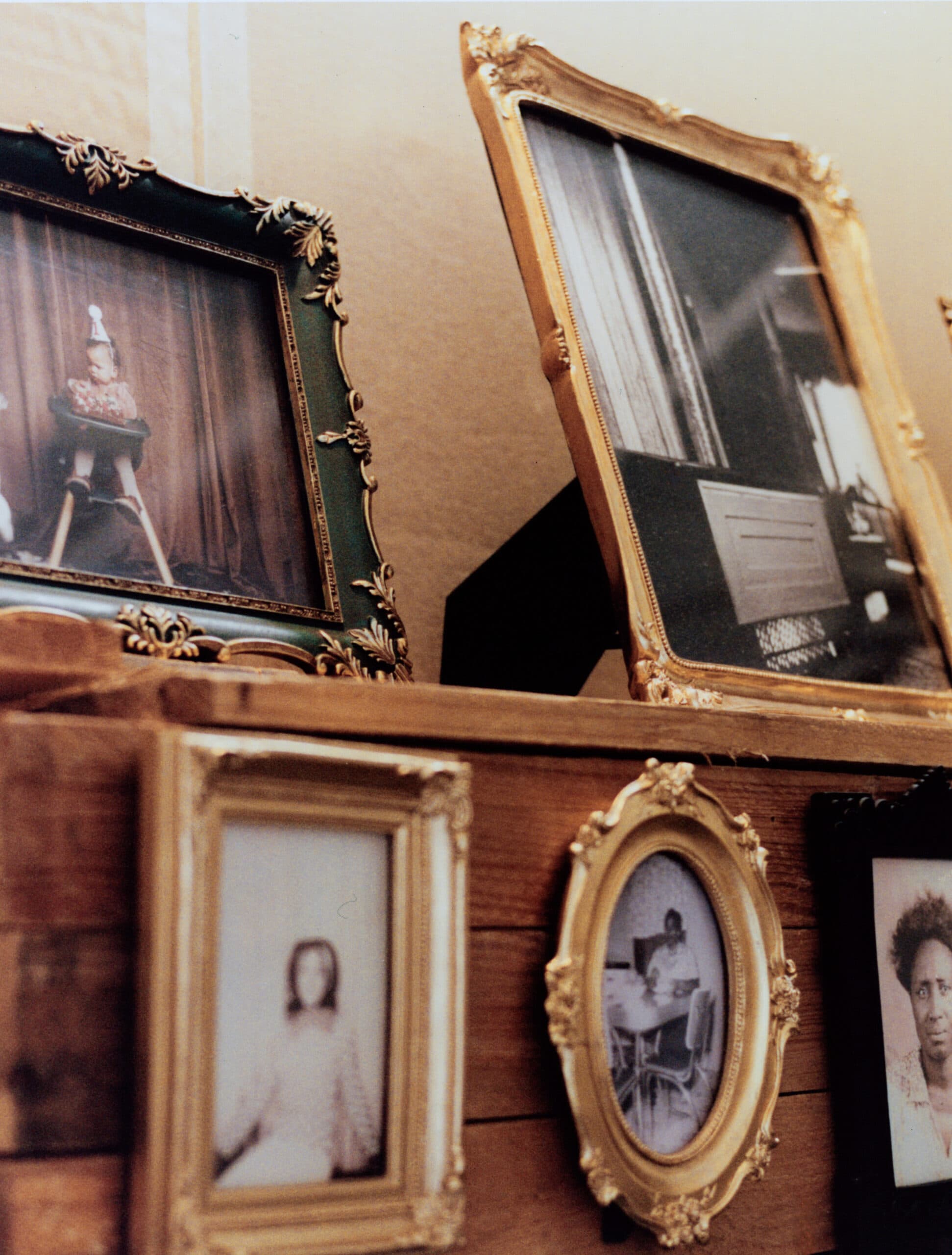 Framed photographs crowd a wooden shelf.